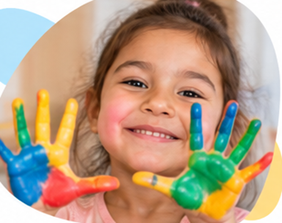 Criança com as mãos coloridas em atividade artística